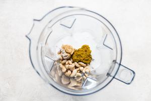 green curry, cashews, coconut milk in the pitcher of a blender.