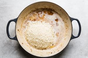 arborio rice being stirred in melted butter in a skillet