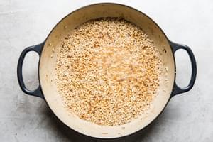 wine and lemon juice added to a pan with arborio rice and melted butter
