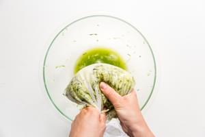hands squeezing zucchini and onion in a nut bag over a bowl