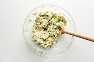 Zucchini Fritter batter in a bowl with a wooden spoon