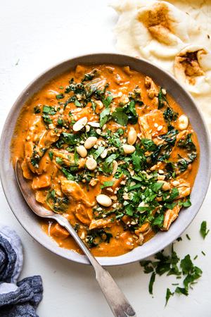 sweet and spicy peanut soup with chicken kale and sweet potatoes in a bowl with naan, sweet potatoes and chicken