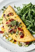 A bacon omelette with avocado and goat cheese topped with microgreens in a list of delicious breakfast ideas