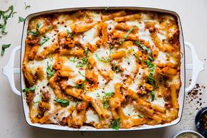 baked ziti in a baking dish topped with fresh basil and parmesan