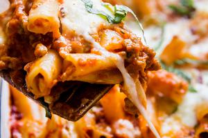 baked ziti in a baking dish topped with fresh basil and parmesan