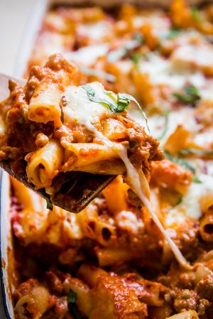 baked ziti in a baking dish topped with fresh basil and parmesan