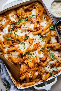 baked ziti in a baking dish topped with fresh basil and parmesan