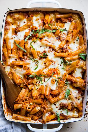 baked ziti in a baking dish topped with fresh basil and parmesan