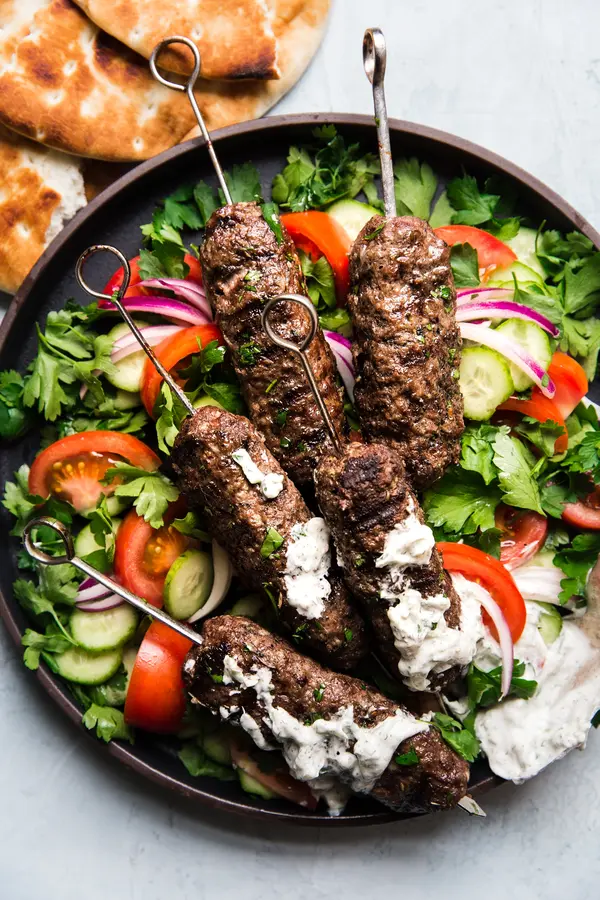 Beef Kofta Kababs with Tzatziki, pita bread and tomatoes on skewers