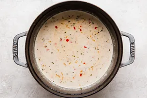 bacon, jalapeño, red bell peppers and onions with beer and stock and cream in a soup pot for beer cheese soup