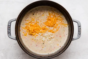 bacon, jalapeño, red bell peppers and onions with beer and stock and cream in a soup pot with cheddar and pepper jack cheese