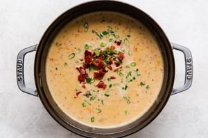 Beer Cheese Soup with bacon, peppers in a bowl with pretzel rolls and a spoon