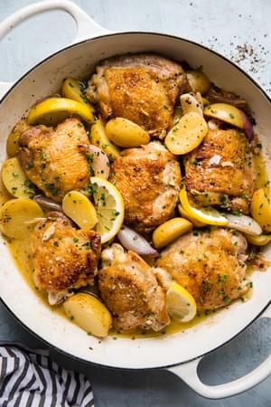 Braised Chicken with Potatoes, shallots, lemons in a white braiser with Chive Butter Sauce