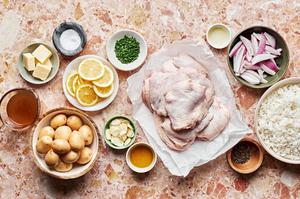 potatoes, skin on chicken thighs, olive oil, lemon slices, shallots, butter, spices and chives in prep bowls on the counter