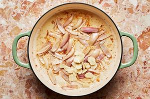 shallots and garlic being cooked in a skillet
