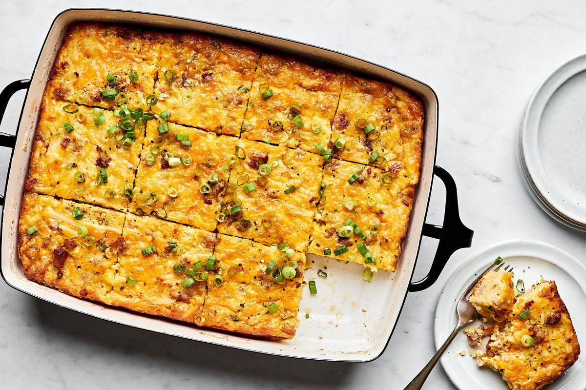 Breakfast casserole with hash browns, ground sausage, eggs, cream, and melted cheese topped with green onions