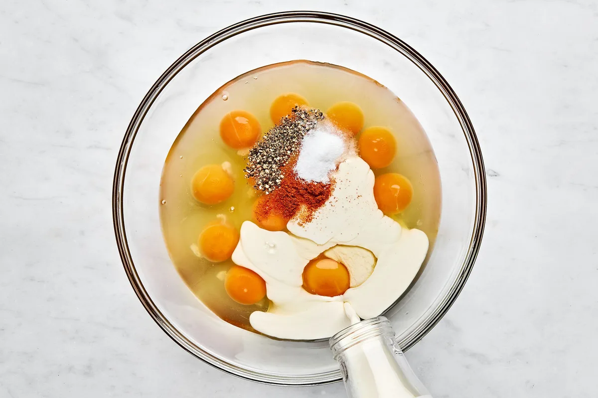 eggs, heavy cream, salt, pepper and cayenne being whisked in a bowl