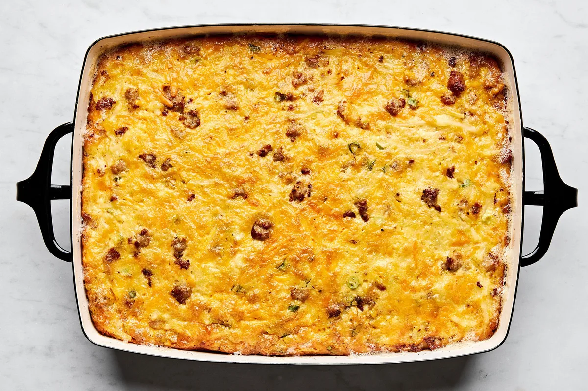Breakfast casserole with hash browns, ground sausage, eggs, cream, and topped with melted cheddar cheese