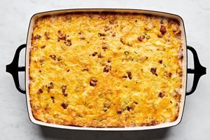 Breakfast casserole with hash browns, ground sausage, eggs, cream, and topped with melted cheddar cheese