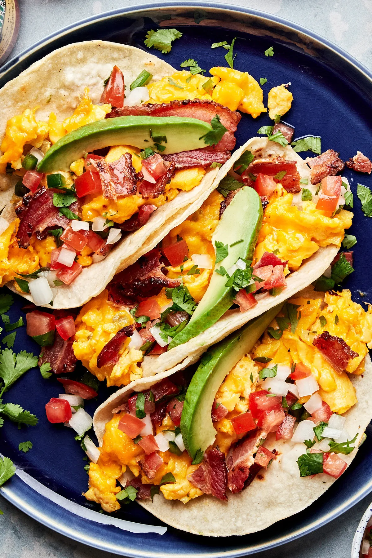 breakfast tacos filled with eggs, bacon, cilantro, sliced avocado and pico de gallo in a list of easy tex-mex brunch recipes