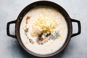 Heavy cream, garlic, Parmesan, Gruyere cheese, fresh thyme and nutmeg in a skillet for Brussels sprout gratin