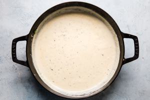 Heavy cream, garlic, Parmesan, Gruyere cheese, fresh thyme, nutmeg and dijon mustard in a skillet for Brussels sprout gratin