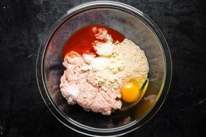 ground chicken, grated onions, an egg, panko, buffalo sauce, salt pepper and spices in a bowl for chicken buffalo meatballs