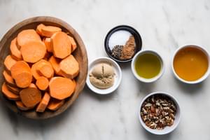sliced sweet potatoes in a bowl, chopped pecans, olive oil, salt cinnamon, nutmeg, black pepper, brown sugar and honey