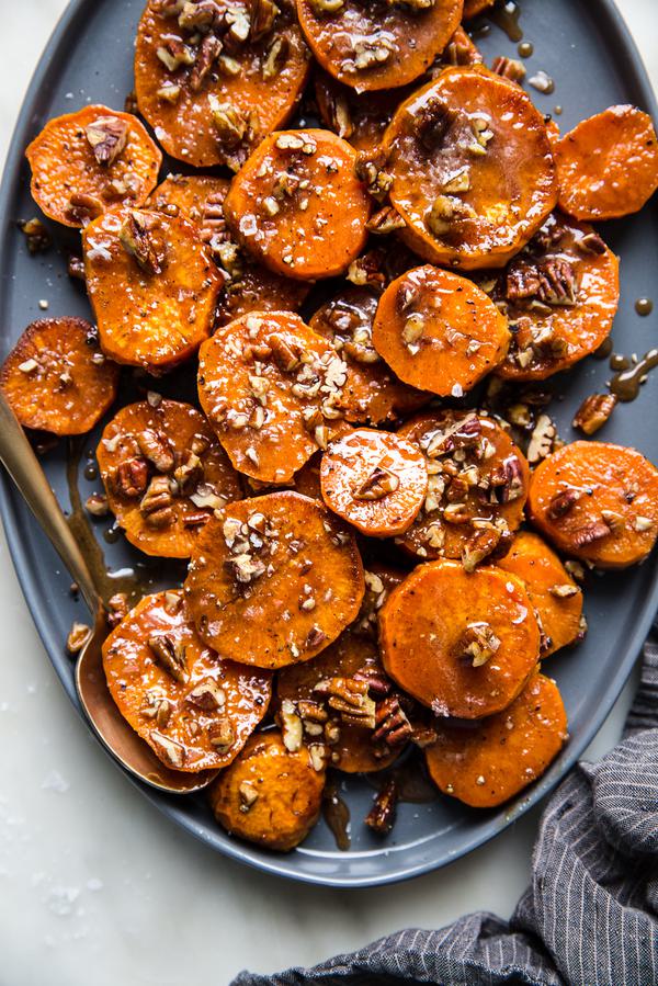 sliced and roasted Candied Yams with Honey, Brown Sugar and pecans on a platter with a serving spoon