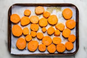 sliced yams on a parchment paper lined baking sheet with olive oil