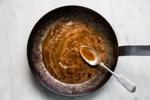 brown sugar, honey, pepper, cinnamon and nutmeg being melted in a skillet, stirred with a spoon