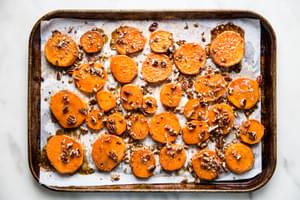 slices of yams on a baking sheet drizzled with honey, brown sugar and chopped pecans