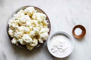 cauliflower, flour and salt in bowls on the counter