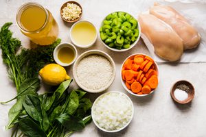 ingredients laid out to make comforting & healthy homemade chicken and rice soup with carrots, celery, spinach and dill.