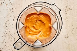 Top-down view of vibrant red Romesco sauce freshly blended in a blende, made from roasted peppers, nuts, and spices