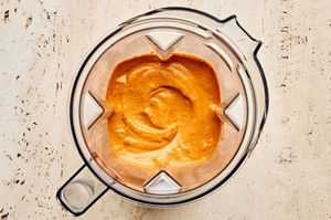 Top-down view of vibrant red Romesco sauce freshly blended in a blende, made from roasted peppers, nuts, and spices