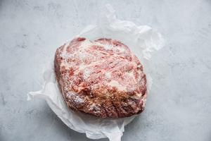 raw pork shoulder on parchment paper, sprinkled with kosher salt