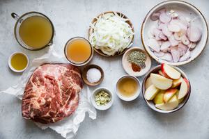 ingredients laid out for cider braised pork shoulder, apples, shallots, fennel, garlic, vinegar, olive oil
