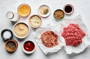 Ground beef, breadcrumbs, onions, eggs, herbs, and spices neatly arranged, ready to create a classic, savory meatloaf.