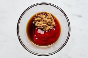 Ketchup, brown sugar, and Worcestershire sauce blending together in a bowl to create a tangy, sweet meatloaf topping.