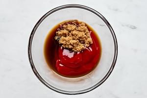 Ketchup, brown sugar, and Worcestershire sauce blending together in a bowl to create a tangy, sweet meatloaf topping.