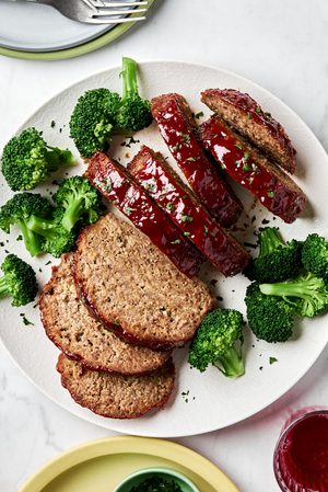 Sliced meatloaf on a plate topped with a brown sugar and ketchup glaze, served with broccoli, a classic comfort food recipe