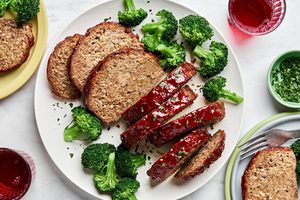 Sliced meatloaf on a plate topped with a brown sugar and ketchup glaze, served with broccoli, a classic comfort food recipe
