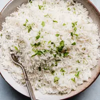 A bowl of creamy coconut rice made with coconut milk, salt, and sugar, garnished with a touch of cilantro