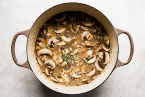 sliced mushrooms, butter, garlic, broth, thyme and onions cooking in a soup pot
