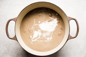 heavy cream being added to a pot of homemade cream of mushroom soup