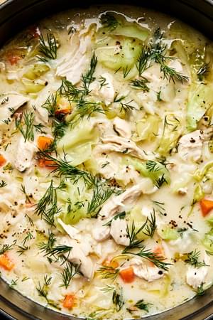 A pot of creamy chicken and rice soup, elegantly topped with fresh dill and black pepper for an extra touch of flavor.