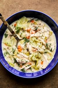 A bowl of creamy chicken and rice soup, elegantly topped with fresh dill and black pepper for an extra touch of flavor.