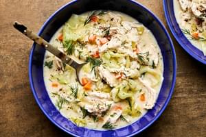 A bowl of creamy chicken and rice soup, elegantly topped with fresh dill and black pepper for an extra touch of flavor.