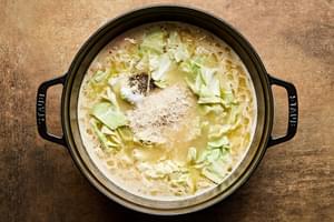 Rice and cabbage added to a pot of well seasoned chicken broth, vegetables and roux to create creamy chicken and rice soup